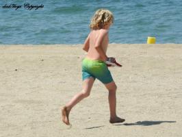 2016-105 Beach blond boy in green short running to the see with his sandals