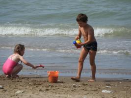 2017-266 Beach boy pouring water of the sea in a bucket near a beach girl