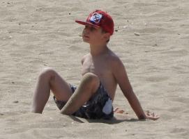 2018-029 boy red cap blue short sitted on the beach