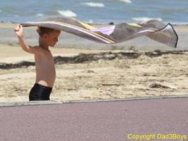 2017-105 Beach boy playing with his towel in the wind