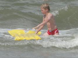 2011 - 59th album - Beachboy in red speedo on his yellow air mattress, fighting against the waves with his black girlfriend
