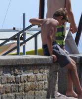 2018-061 Boy shirtless in gray short sit on a wall near the beach